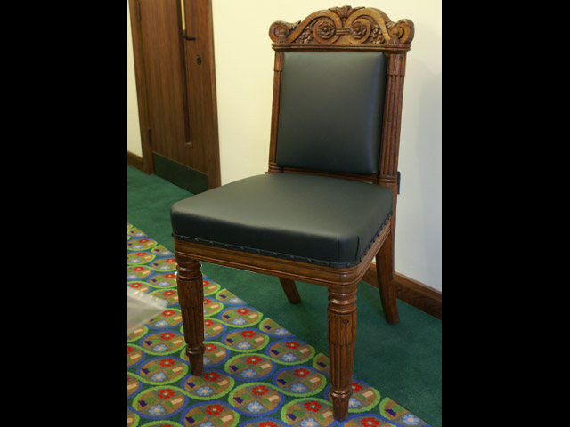 One of a set of dining chairs upholstered in green leather.